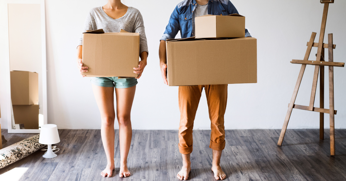 Millennial homebuyer standing with boxes